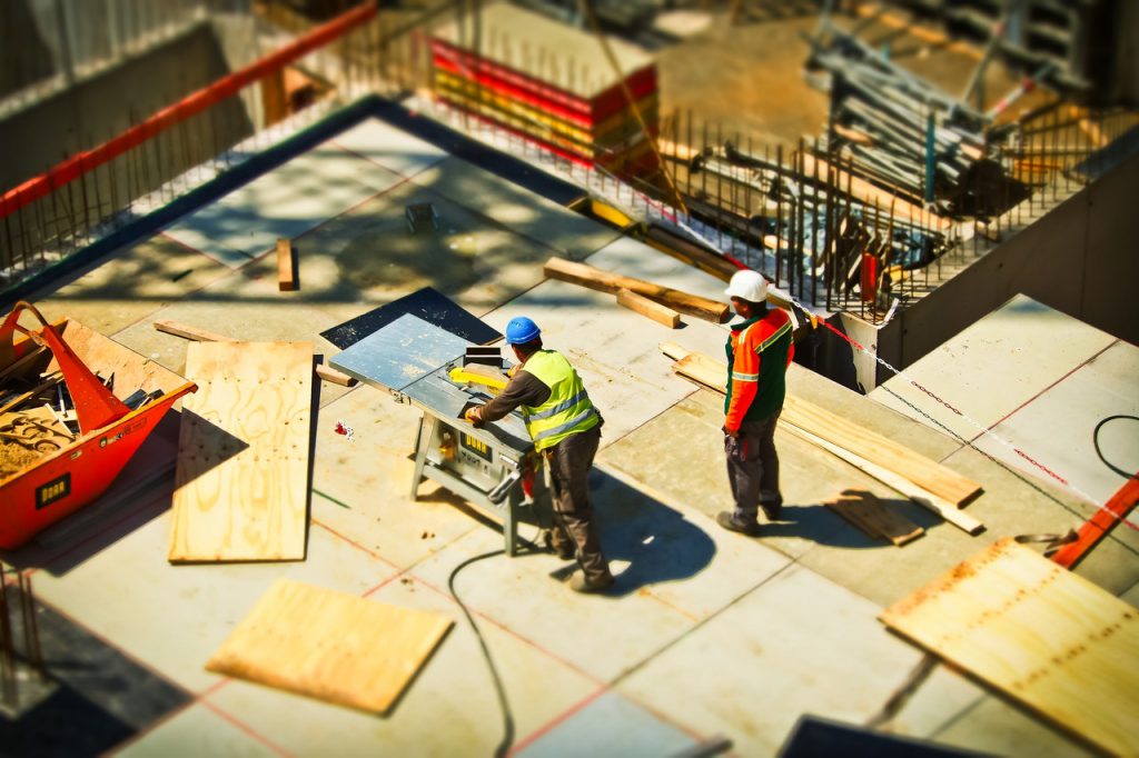 Two construction workers in hard hats and reflective gear on a job site. 