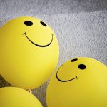 Yellow balloons with smiley faces on them.