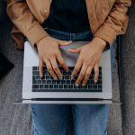 Aerial view of person typing on laptop keyboard.