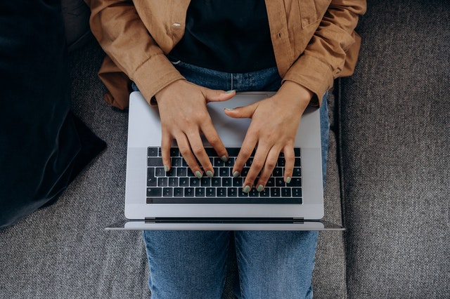 Aerial view of person typing on laptop keyboard.