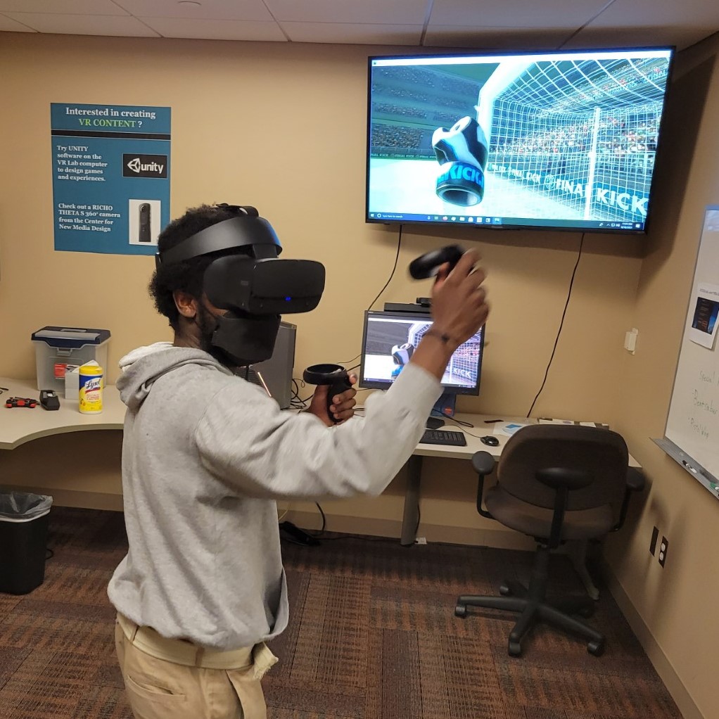 Center for New Media Design student worker, Terry, playing a soccer game in the VR Lab.