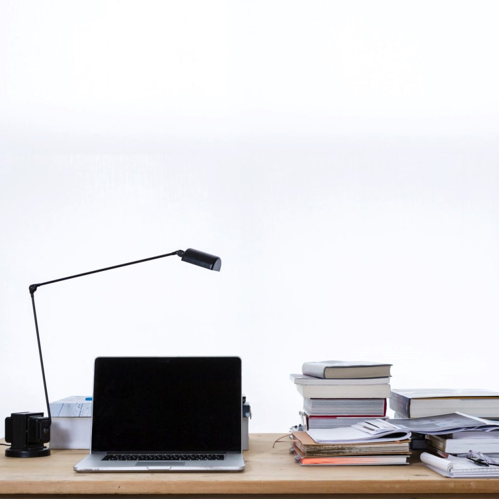 Laptop on desk book stacks.